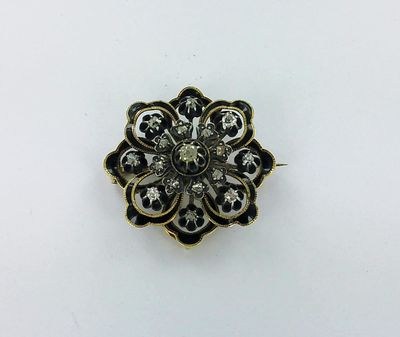 un gros plan sur une broche en forme de fleur dorée et noire