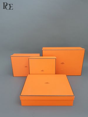 trois boîtes orange empilées les unes sur les autres sur une surface grise