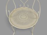 a white metal chair with a circular design on the back