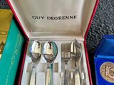 silverware in a red box on a carpeted floor next to other silverware