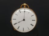 a small gold pocket watch on a black surface