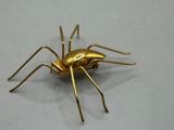 a gold spider that is sitting on a white surface