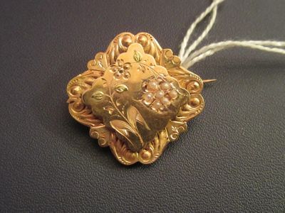 a gold heart shaped brooch on a white string