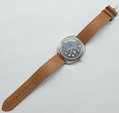 gros plan d'une montre sur une surface blanche avec un bracelet marron