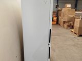 a white refrigerator sitting in a warehouse with boxes in the background