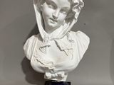 a white bust of a woman on a blue base