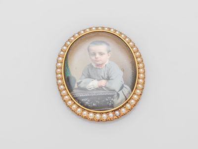 an old picture of a young boy with pearls in a gold frame