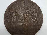 une vieille médaille en bronze sur laquelle figurent une femme et deux hommes