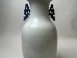 a white vase with blue flowers in it on a table