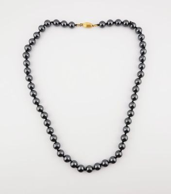 a black pearl necklace with a gold clasp on a white background