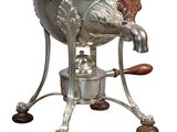 a silver kettle with a lion on it on a stand