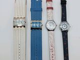 quatre montres de couleurs différentes sont alignées sur une surface blanche
