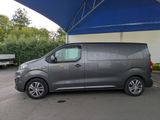 the grey van is parked under a blue tent in a parking lot