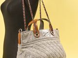 une femme tenant un sac à main gris, posée sur un mannequin