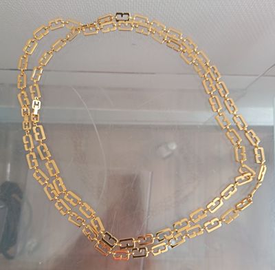 a gold necklace with a cross on it in a display case