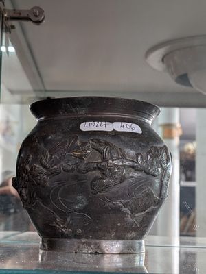 a black vase on display in a glass case