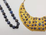 a close up of a necklace and a bead necklace on a table