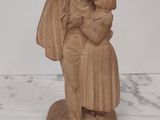 une statue de femme tenant un enfant sur une table