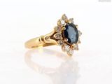 a close up of a gold ring with a blue sapphire and white diamonds