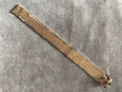 un gros plan d'un bracelet en or posé sur un tissu gris