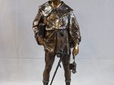 bronze statue of a man with a cane and hat on a white background