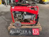 un générateur rouge posé sur une palette dans un garage