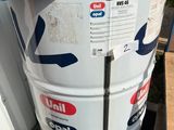 un grand fût blanc posé sur une palette, à côté d'un conteneur bleu