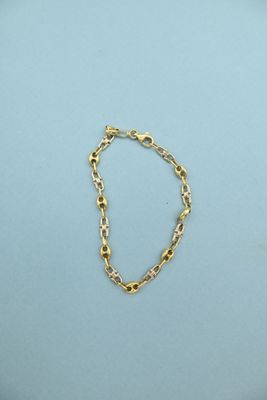 a close up of a gold chain bracelet on a blue surface