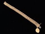 a close up of a gold bracelet with a coin on it