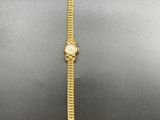 a gold watch on a black surface with a white background