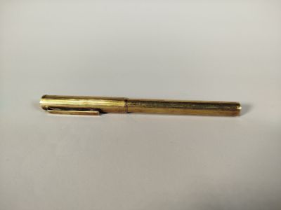 a gold pen sitting on top of a white surface