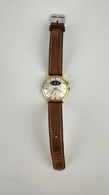 gros plan d'une montre sur une surface blanche avec un bracelet marron