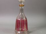 a pink glass bottle with a gold top on a white surface