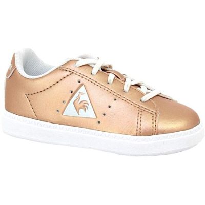 La chaussure de tennis de la petite fille est dorée et blanche, avec un triangle sur le côté.