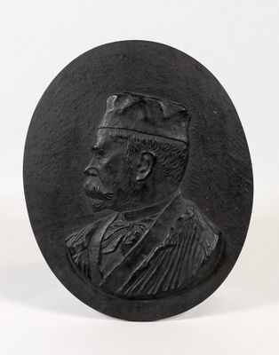 un gros plan sur une plaque en pierre noire représentant un homme coiffé d'un chapeau