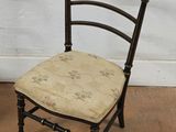 a black chair with a floral seat pad on a tile floor