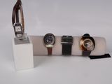 three watches and a watch case on display on a white surface