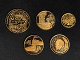 four gold coins with different designs on them on a black surface