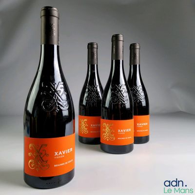 quatre bouteilles de vin sont alignées sur une surface blanche