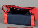 an orange and blue purse sitting on top of a gray surface