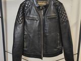 une veste en cuir noir accrochée à un porte-manteau dans une pièce