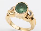a close up of a gold ring with a green tourmaline and diamonds