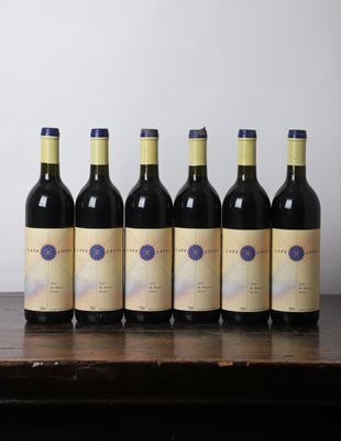 six bottles of wine are lined up on a wooden table