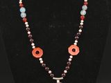 un collier orné d'un pendentif en pierre rouge, blanche et bleue, posé sur un mannequin noir