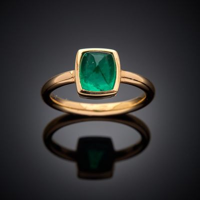 a close up of a gold ring with an emerald stone