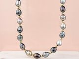 a necklace made of black and white pearls and gold beads