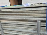 a pile of steel bars stacked on top of each other in front of a building