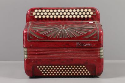 an old red accordion sitting on top of a white table