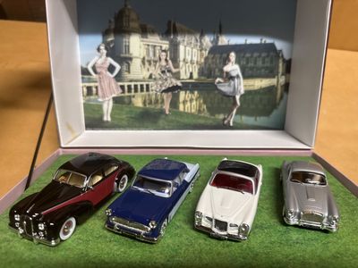 quatre petites voitures posées dans une boîte sur une table
