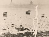 a black and white photo of a man standing on the beach